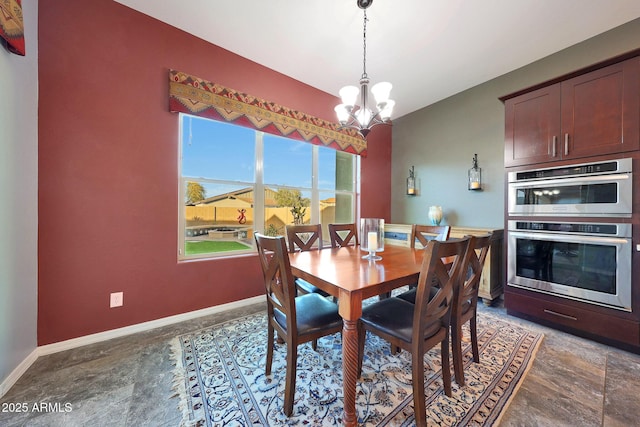 dining room with baseboards, stone finish floor, and a notable chandelier