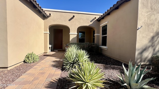 entrance to property featuring a tile roof and stucco siding