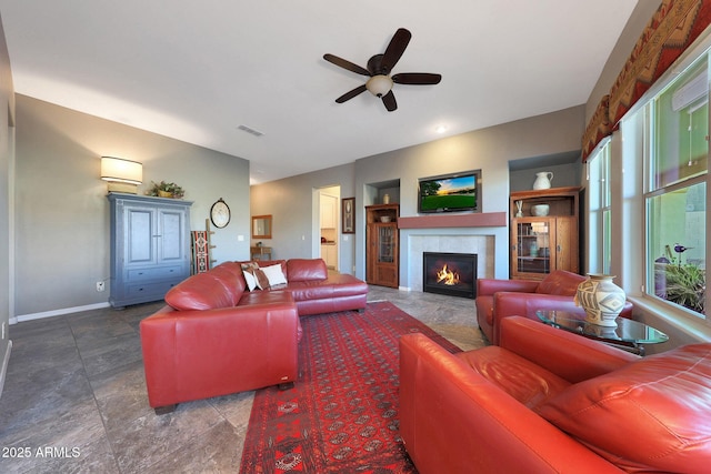 living room featuring ceiling fan, a fireplace, visible vents, and baseboards