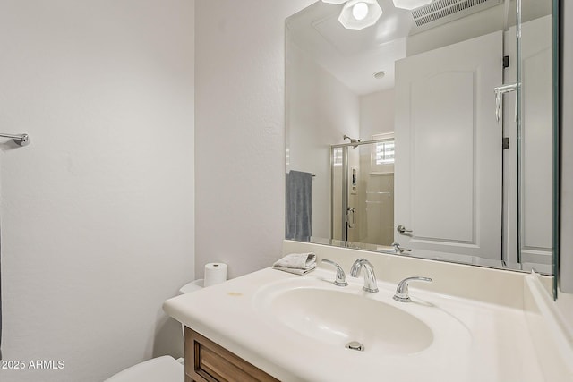 bathroom with toilet, vanity, and a shower with shower door