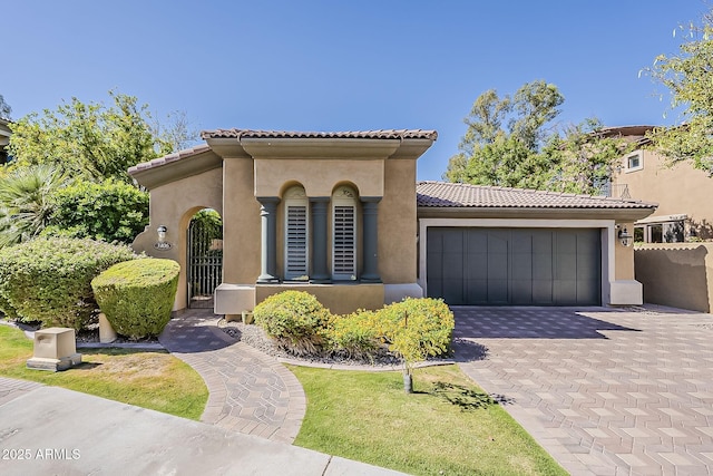mediterranean / spanish-style house featuring a tile roof, an attached garage, and stucco siding