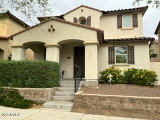mediterranean / spanish home featuring a tiled roof and stucco siding