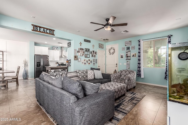 living room featuring light tile patterned floors, visible vents, baseboards, and a ceiling fan