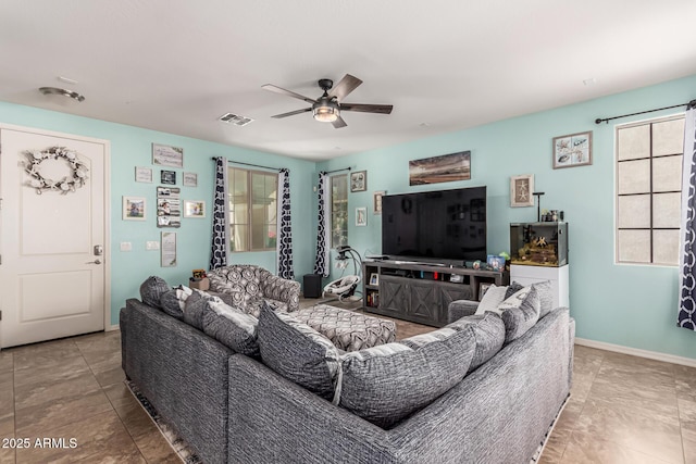 living area featuring baseboards, a ceiling fan, and visible vents