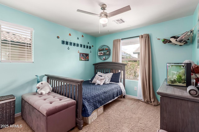 carpeted bedroom featuring baseboards, a ceiling fan, and visible vents