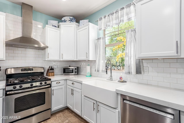 kitchen with light countertops, wall chimney exhaust hood, a sink, and appliances with stainless steel finishes