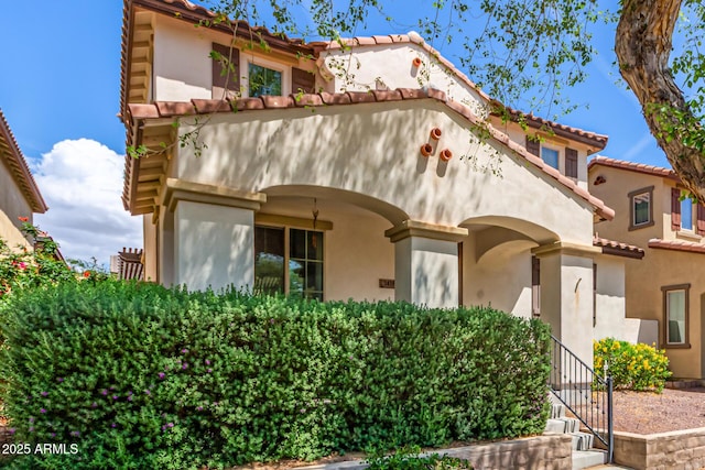 mediterranean / spanish house featuring a tile roof and stucco siding