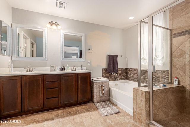 full bath featuring double vanity, a stall shower, visible vents, a bath, and a sink