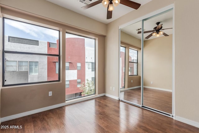 unfurnished bedroom featuring wood finished floors, baseboards, a closet, and a ceiling fan