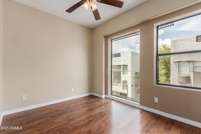 empty room featuring wood finished floors, a ceiling fan, and baseboards