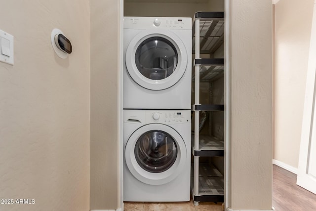laundry room featuring stacked washer / drying machine and baseboards