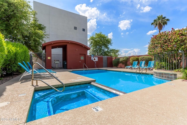 community pool with a hot tub, a patio area, and fence