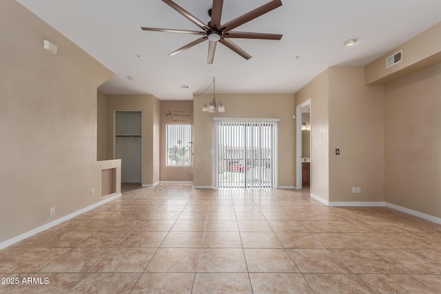 spare room featuring a chandelier, ceiling fan, light tile patterned floors, and baseboards