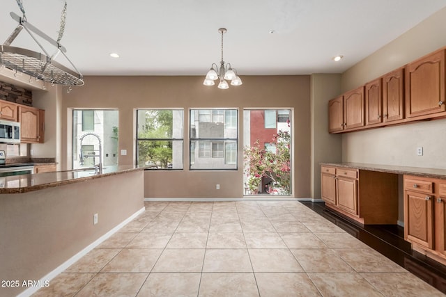kitchen with stainless steel electric range oven, light tile patterned floors, pendant lighting, a sink, and a chandelier