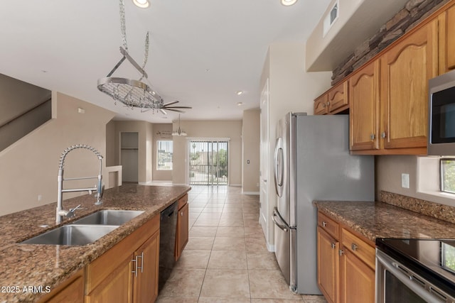 kitchen with a sink, dark stone counters, stainless steel appliances, light tile patterned flooring, and recessed lighting