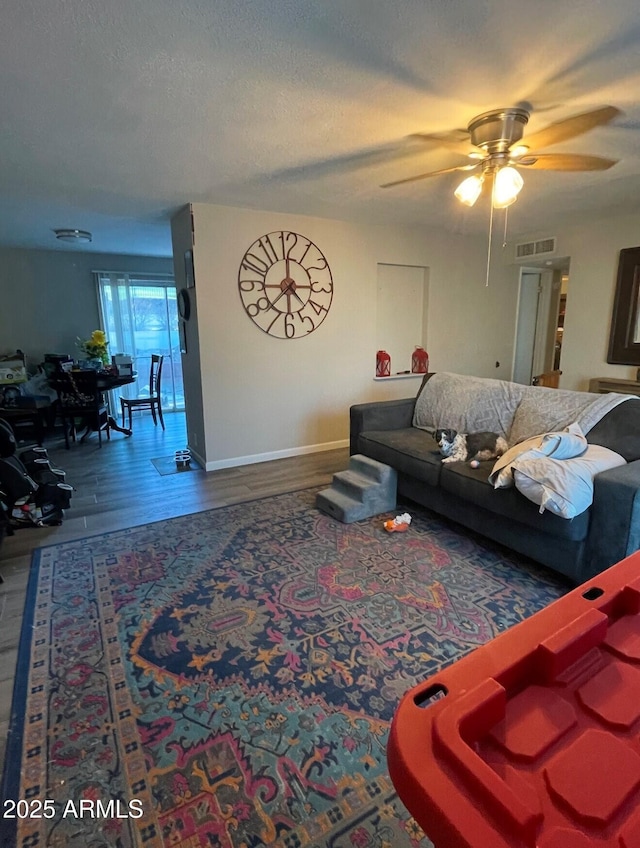 living room featuring ceiling fan, dark wood-type flooring, and a textured ceiling