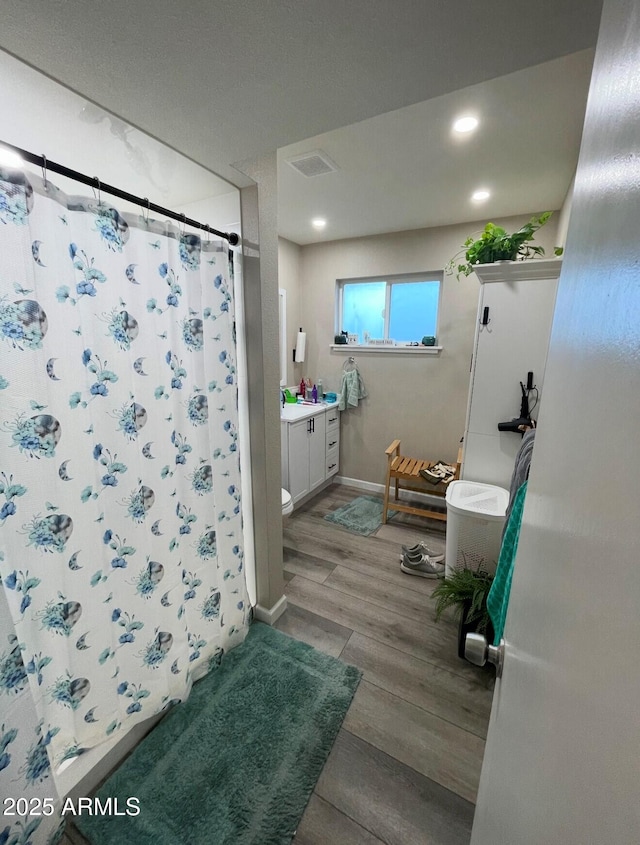 bathroom featuring wood-type flooring, toilet, a shower with shower curtain, and vanity