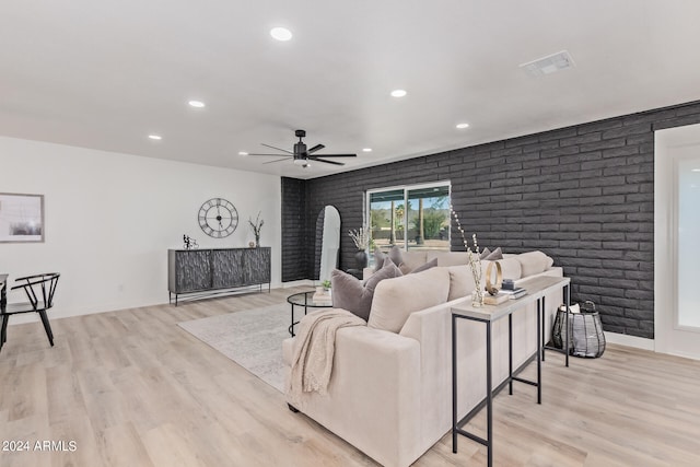 living room with ceiling fan, light hardwood / wood-style floors, and brick wall