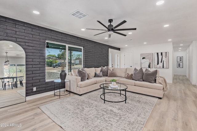 living room featuring ceiling fan, light hardwood / wood-style floors, and brick wall