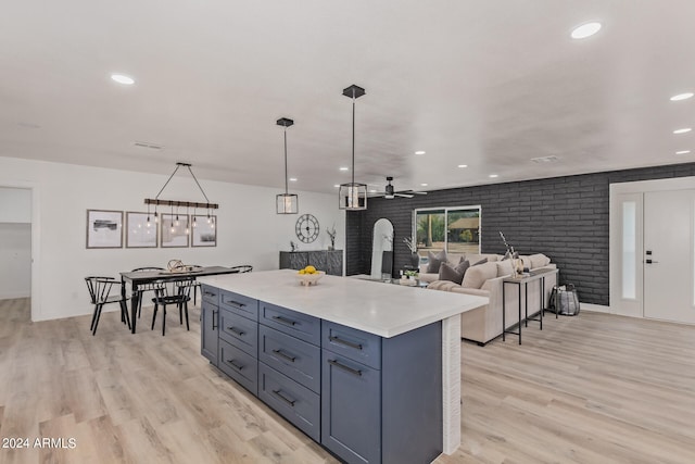 kitchen with decorative light fixtures, light wood-type flooring, brick wall, a kitchen island, and ceiling fan