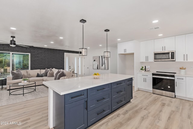 kitchen featuring decorative light fixtures, appliances with stainless steel finishes, light hardwood / wood-style floors, brick wall, and white cabinetry