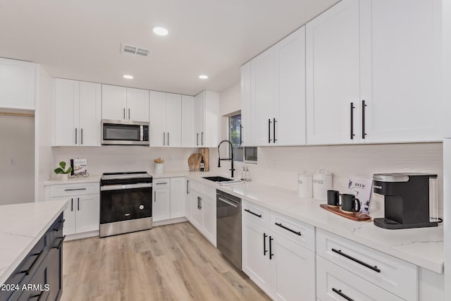 kitchen with white cabinets, sink, stainless steel appliances, and light hardwood / wood-style floors