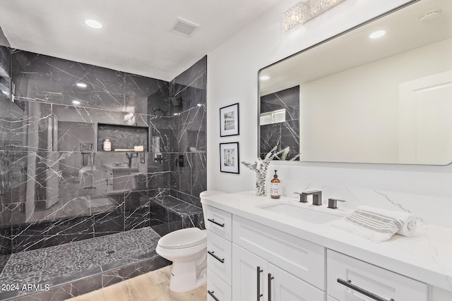 bathroom with hardwood / wood-style floors, oversized vanity, toilet, and a tile shower