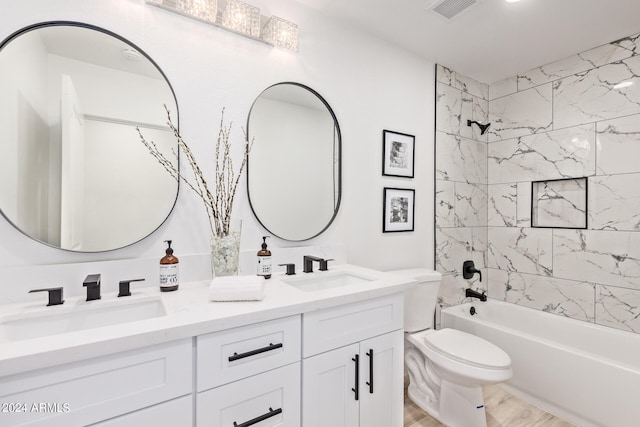 full bathroom featuring toilet, tiled shower / bath, and double sink vanity