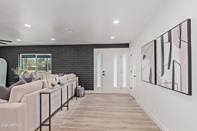 living room featuring brick wall, ceiling fan, and light wood-type flooring