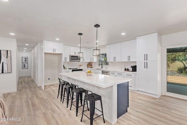 kitchen featuring appliances with stainless steel finishes, a center island, light wood-type flooring, and white cabinetry