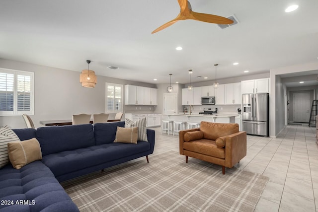 living room featuring ceiling fan, light tile patterned floors, and sink