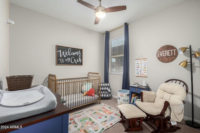 carpeted bedroom with a crib and ceiling fan