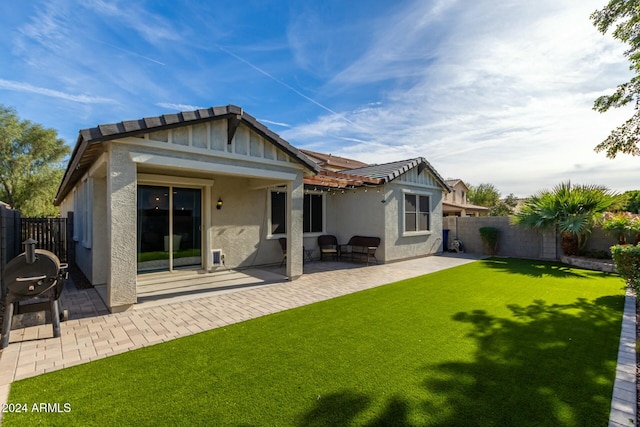 rear view of house featuring a patio area and a yard