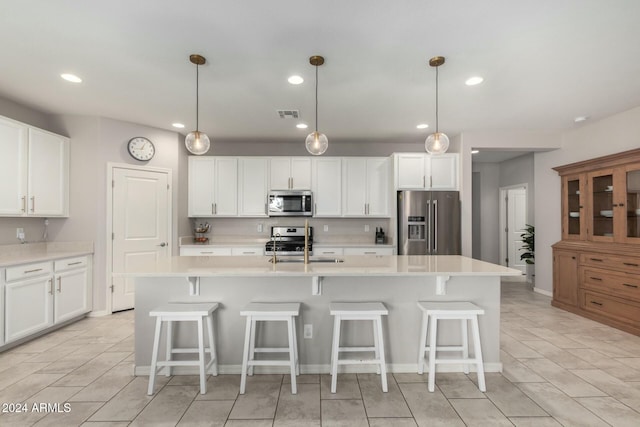 kitchen with white cabinets, appliances with stainless steel finishes, and a kitchen island with sink