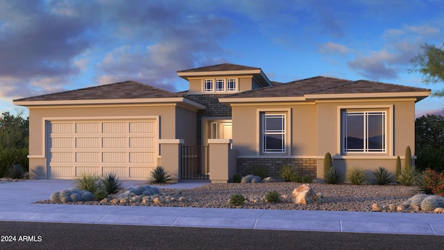 prairie-style home with stone siding, concrete driveway, an attached garage, and stucco siding