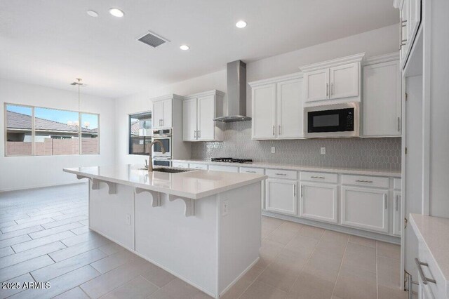 kitchen with built in microwave, white cabinets, light countertops, and wall chimney exhaust hood