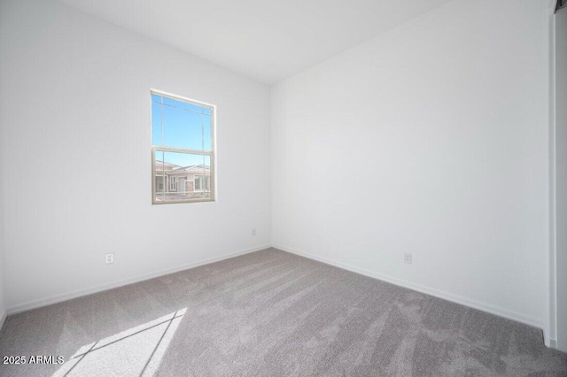 carpeted spare room featuring baseboards