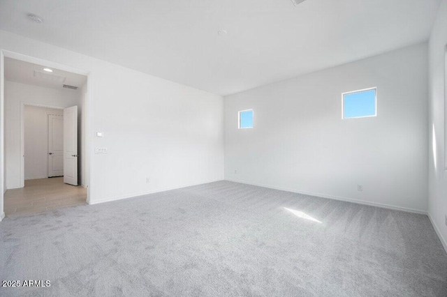 spare room with baseboards and light colored carpet