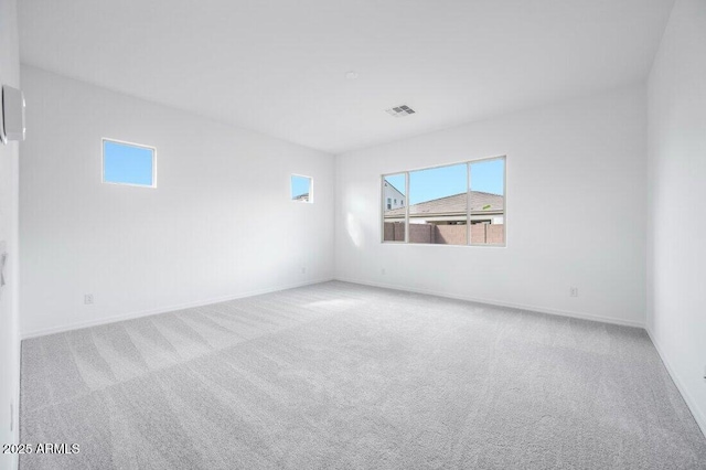 empty room featuring light carpet, baseboards, and visible vents