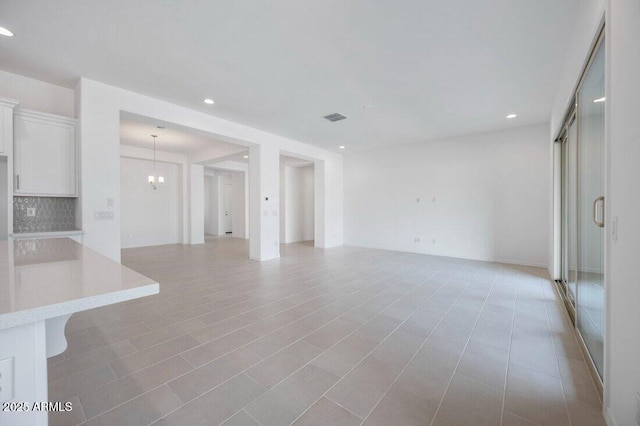 unfurnished living room featuring recessed lighting, visible vents, and a notable chandelier