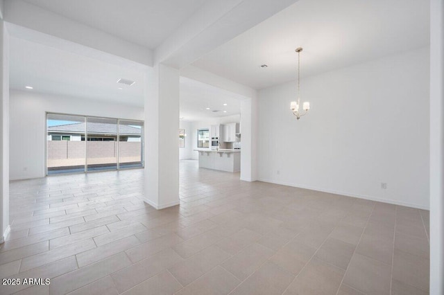 unfurnished living room with plenty of natural light, a chandelier, and baseboards