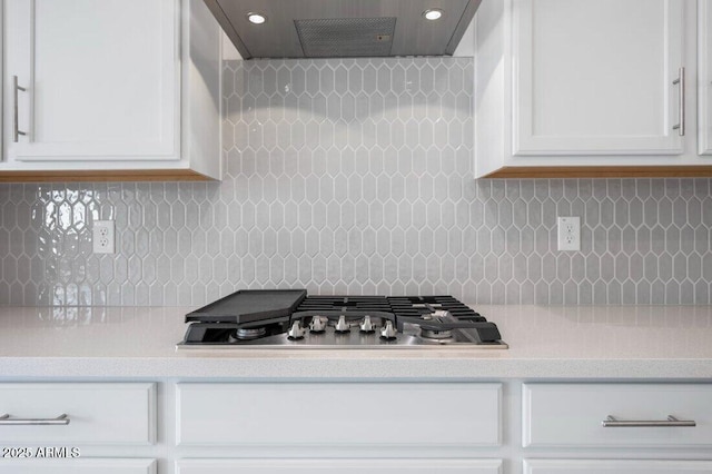 kitchen with light countertops, wall chimney range hood, stainless steel gas stovetop, and white cabinets