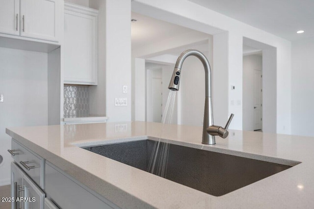 kitchen featuring white cabinetry, backsplash, a sink, and recessed lighting