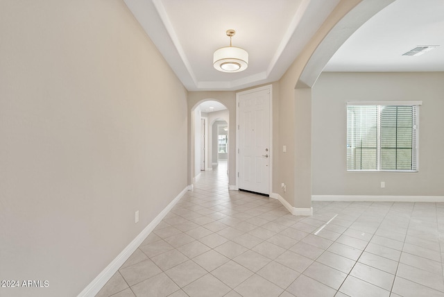 entryway featuring light tile patterned floors and a raised ceiling