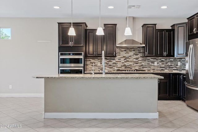 kitchen featuring appliances with stainless steel finishes, hanging light fixtures, wall chimney exhaust hood, and tasteful backsplash