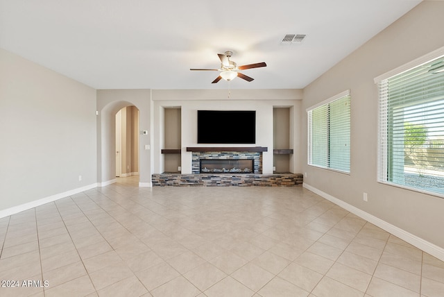 unfurnished living room featuring ceiling fan, a fireplace, and light tile patterned floors