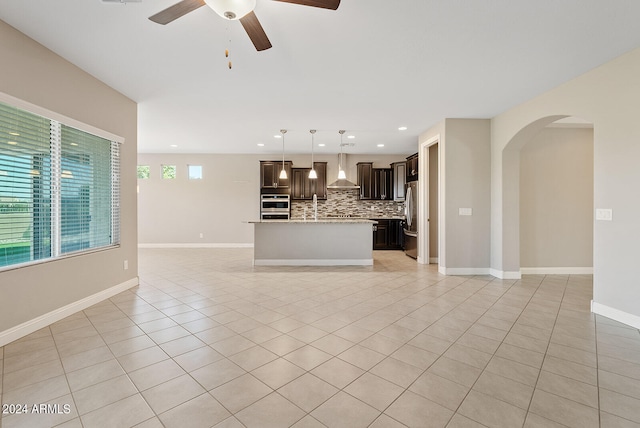 kitchen with backsplash, a center island, decorative light fixtures, appliances with stainless steel finishes, and wall chimney exhaust hood