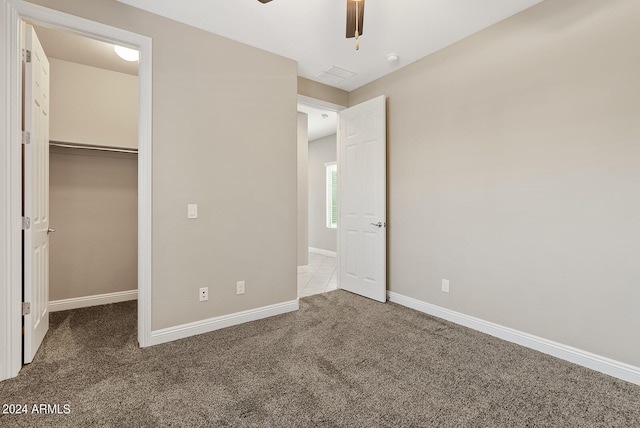 unfurnished bedroom featuring a spacious closet, carpet floors, ceiling fan, and a closet