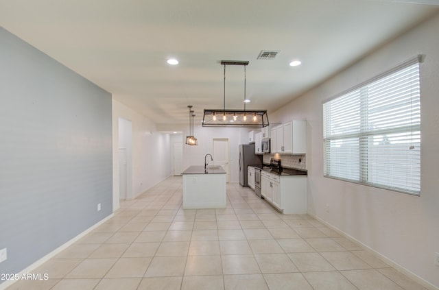 kitchen with light tile patterned floors, stainless steel appliances, dark countertops, tasteful backsplash, and visible vents