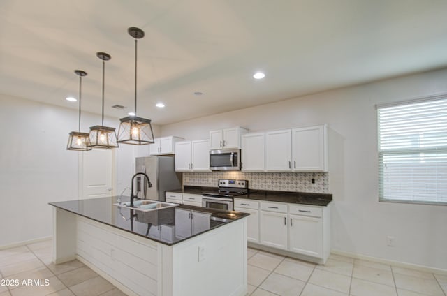 kitchen with tasteful backsplash, dark countertops, appliances with stainless steel finishes, white cabinetry, and a sink